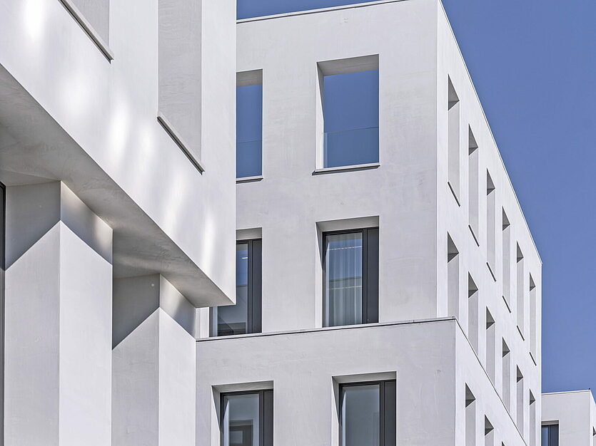 Modern white façade with deep window reveals in sunlight, detail view of JED Schlieren