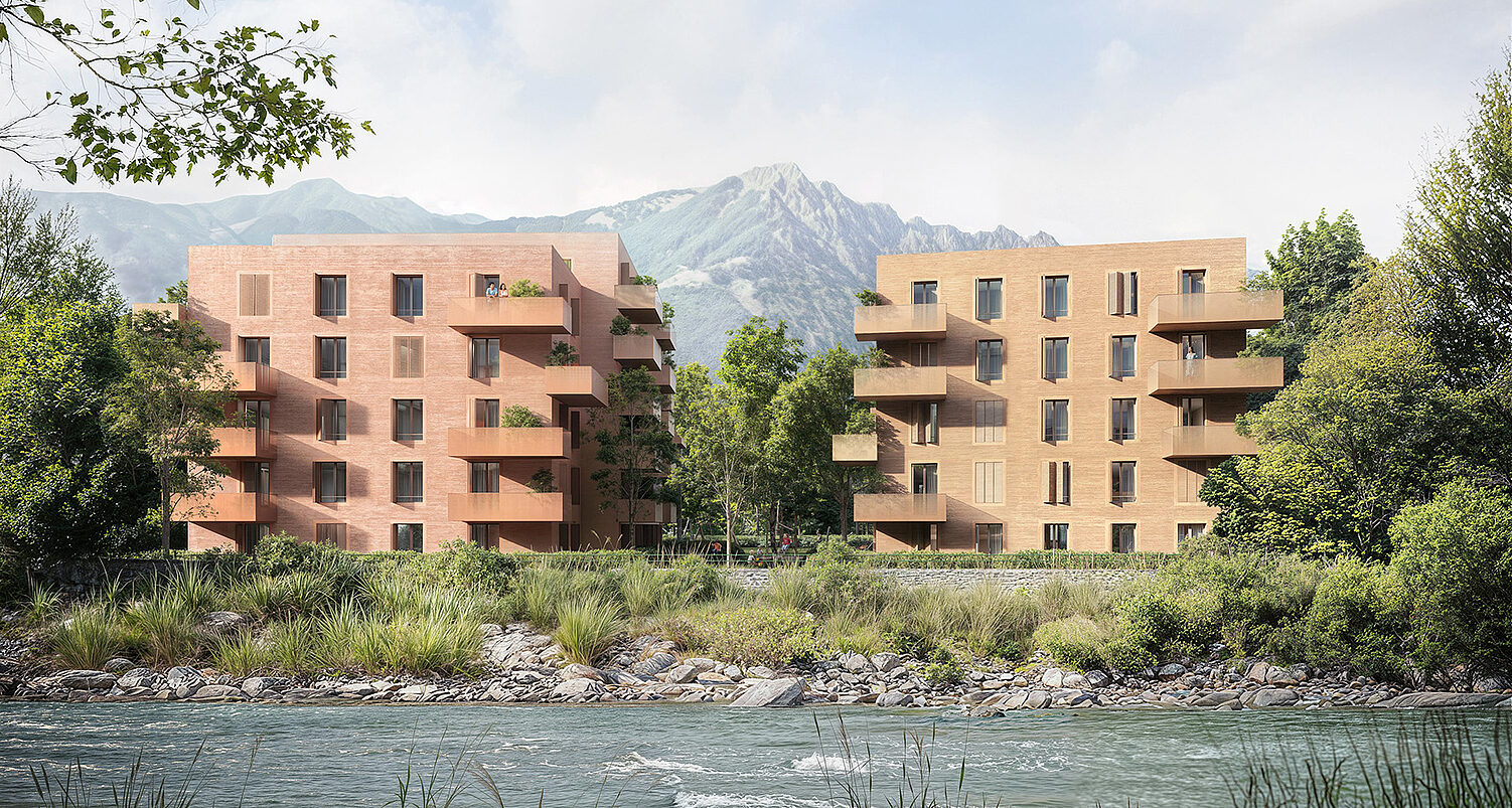 Zwei moderne Wohngebäude am Fluss, umgeben von Bäumen und Bergen im Hintergrund.