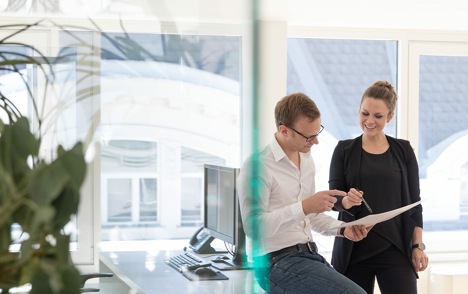 Architects discussing a document together by the window in a bright office