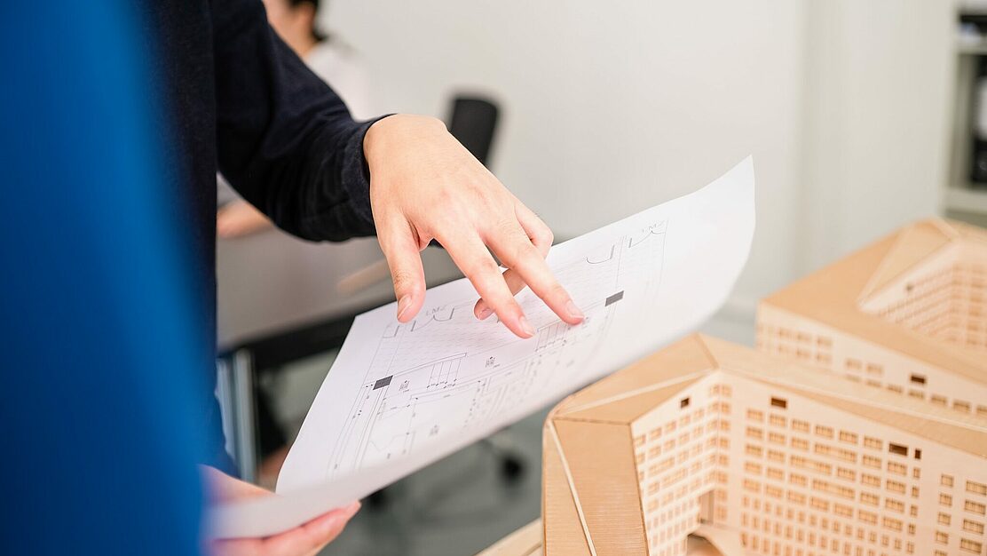 Architektin analysiert technische Zeichnungen im Planungsprozess eines neuen Projekts
