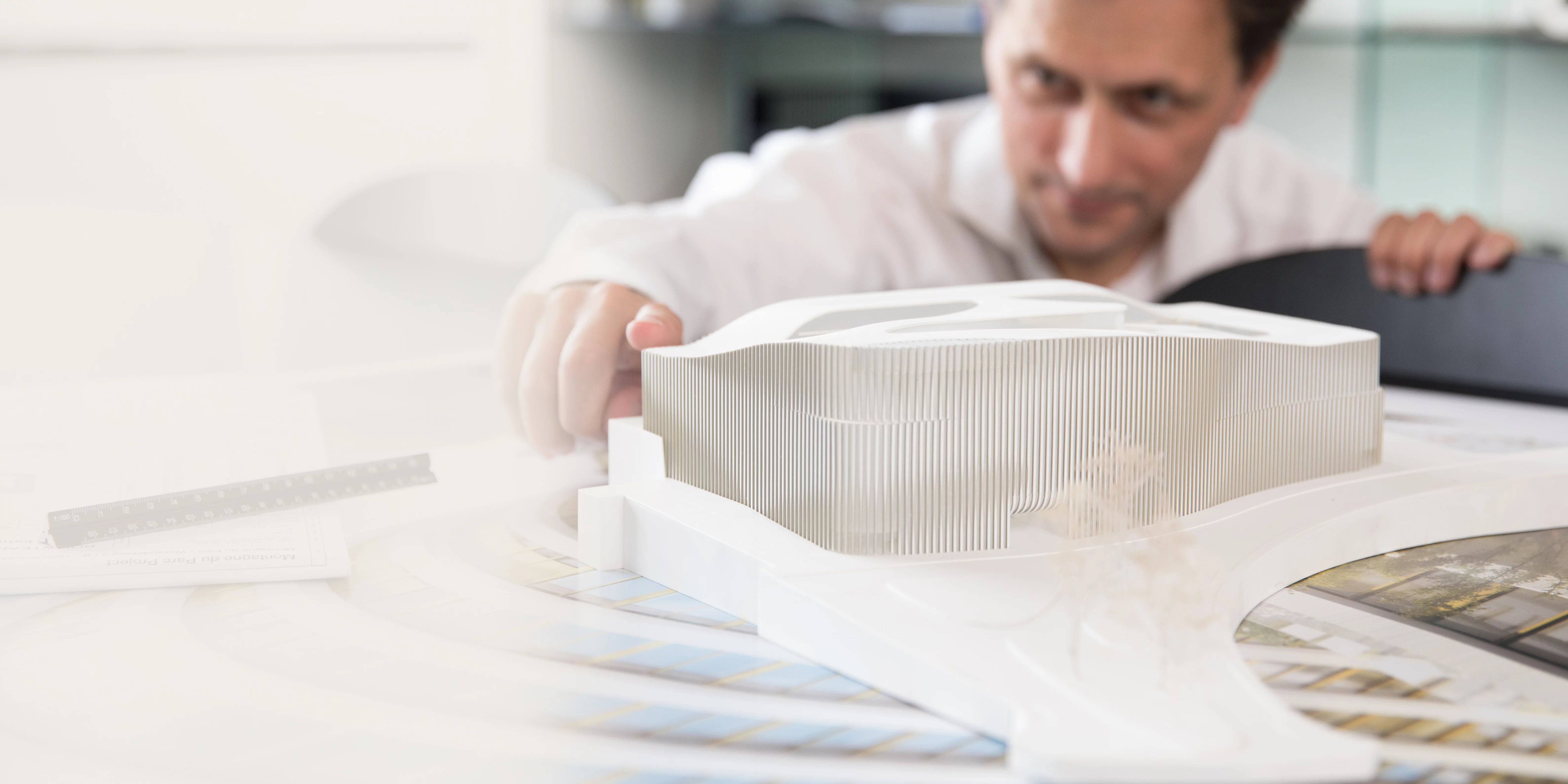 Architekt arbeitet konzentriert an einem detaillierten Architekturmodell am Schreibtisch