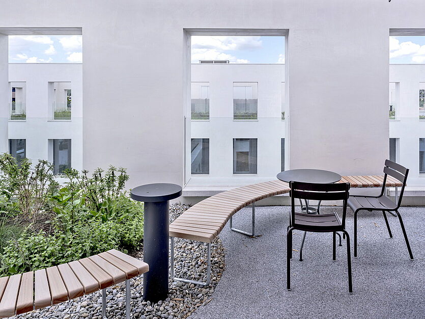 Terrace at JED Schlieren with bench, chairs and plants in front of white wall