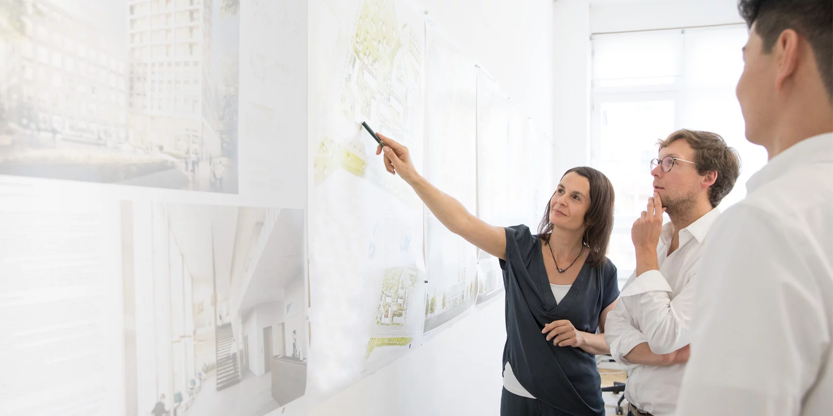 Architektin präsentiert Pläne an der Wand und diskutiert mit Kollegen ein Projekt